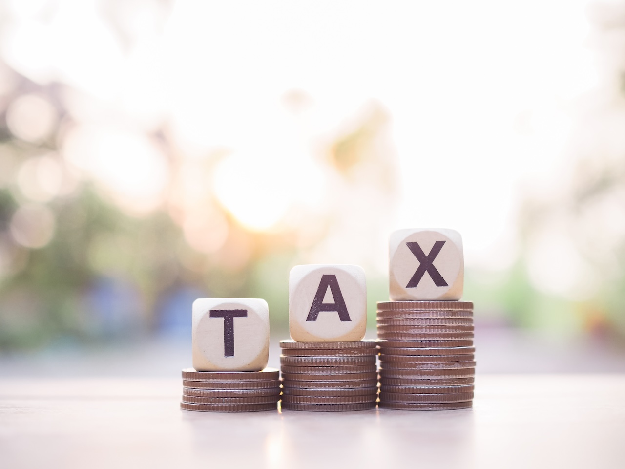 Wooden blocks with the word TAX and stack of coins. The concept about saving money and manage time to paying tax